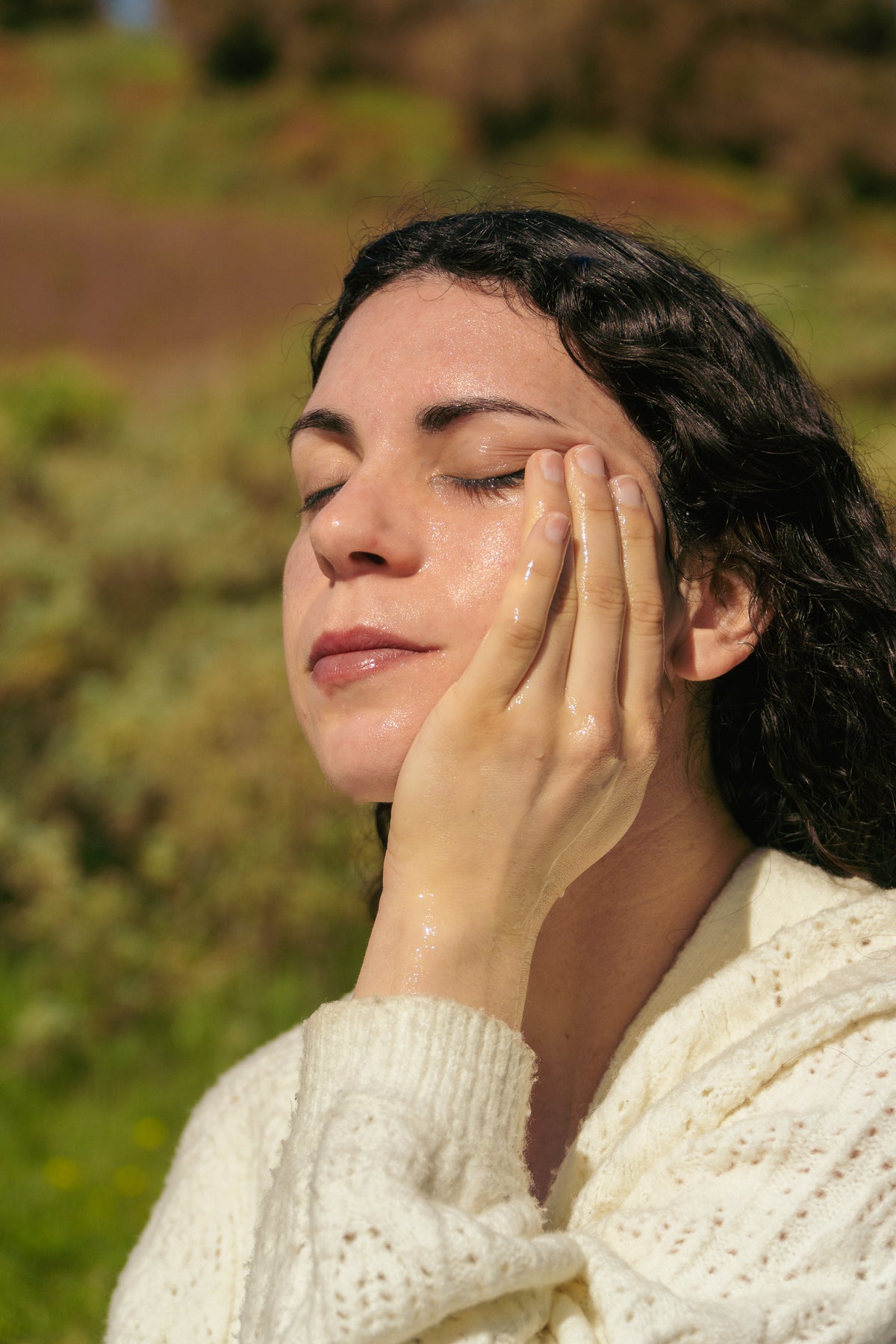Mujer aplicando cosmética natural de wildpretii sobre el rostro, al aire libre en Tenerife